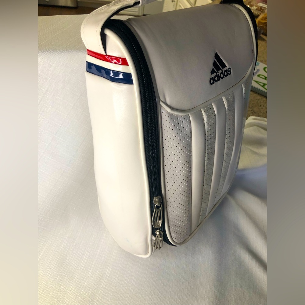 Adidas white perforated stripe bag with top handle and red/white/blue trim.